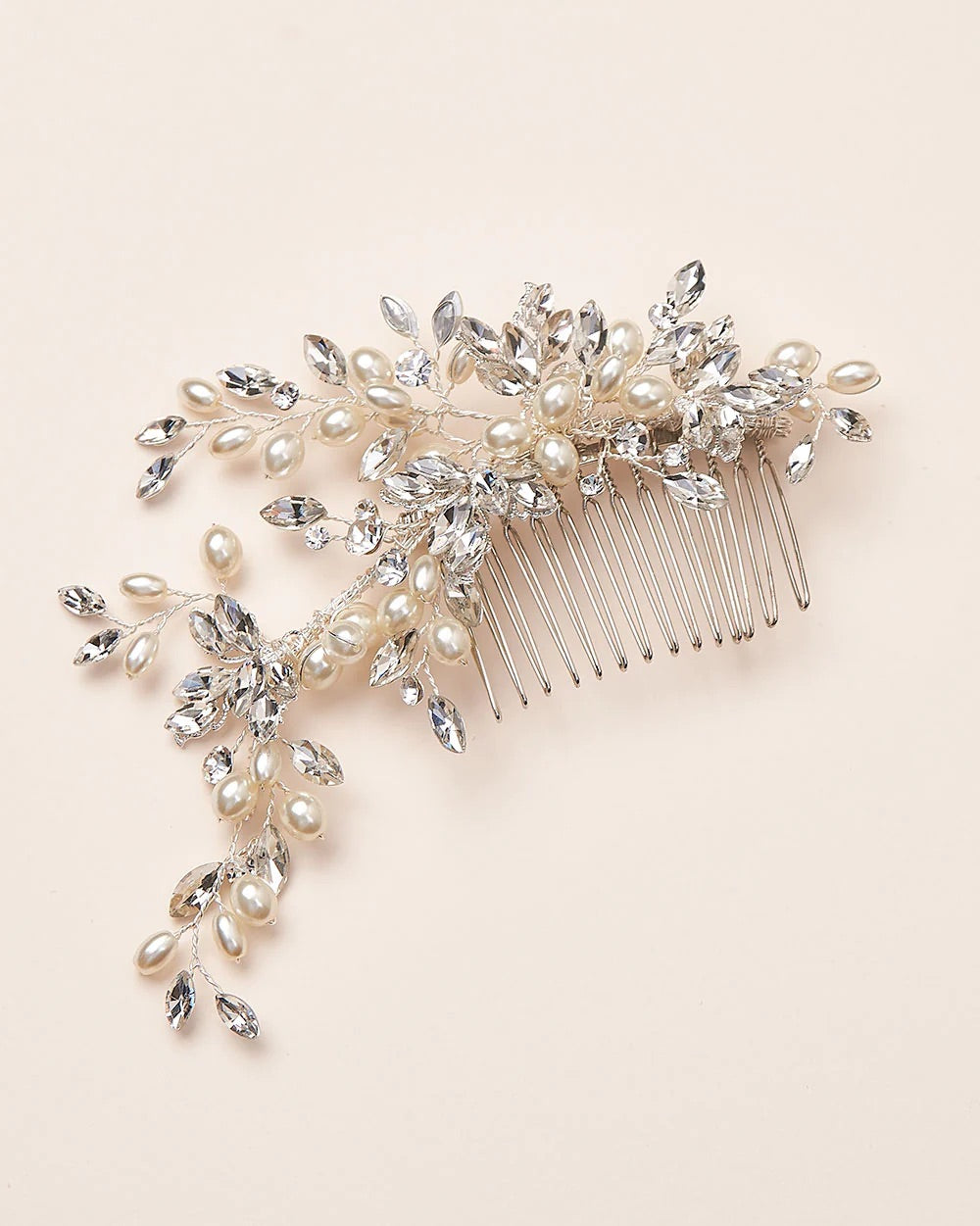A bridal hair comb featuring ivory pearls and silver wire wrapped branches of marquis stones on a metal wire comb.