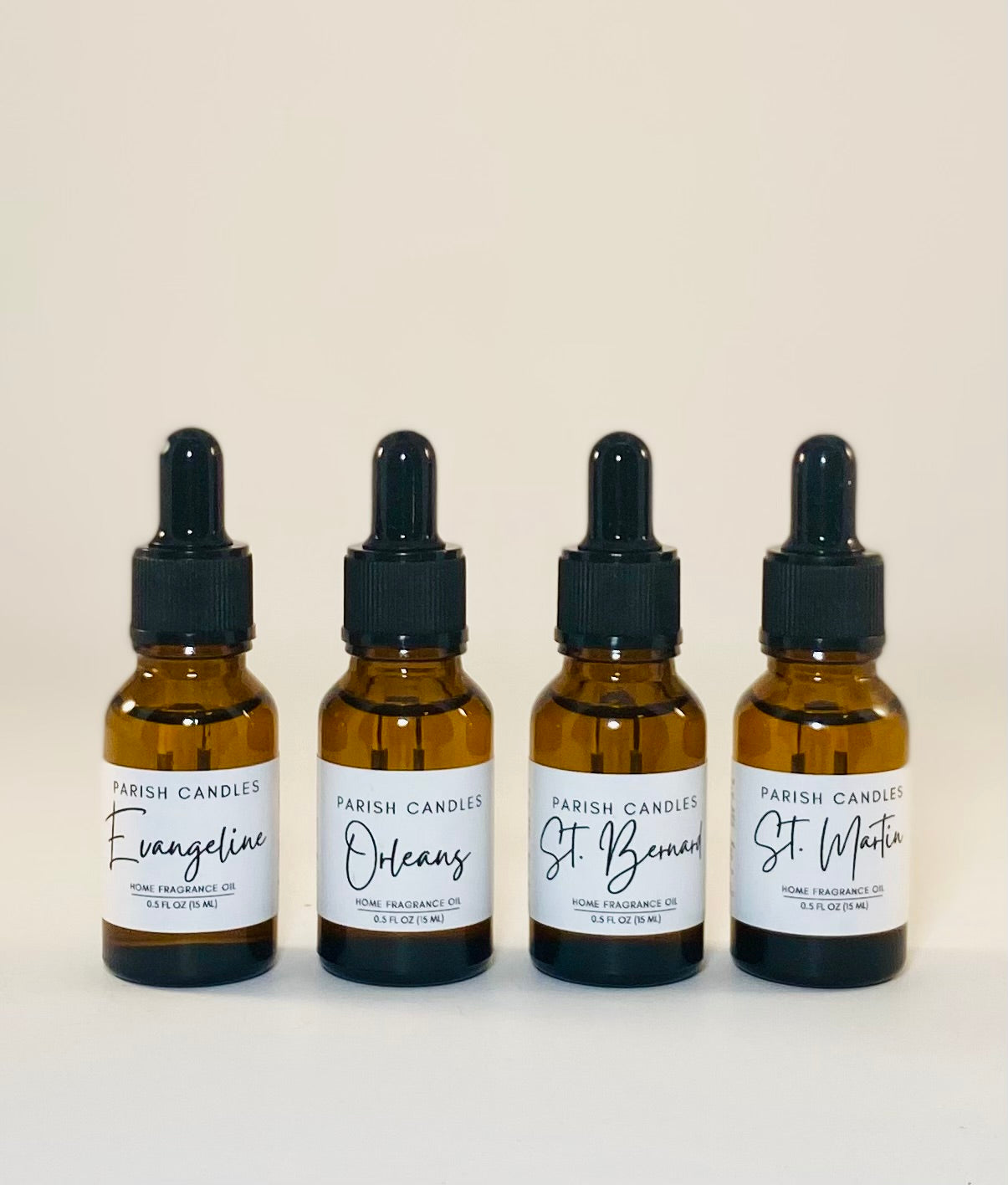 Four amber glass bottles with black dropper lids, labeled as Parish Candles home fragrance oils. Evangeline, Orleans, St Bernard and St Martin are written on the labels.