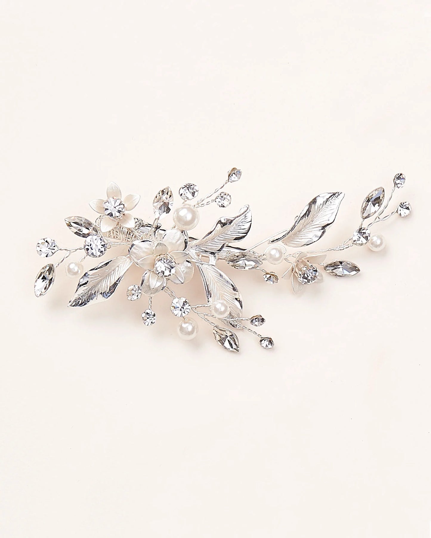 A bridal hair clip with a floral design, pearls, and crystals in a silver color.
