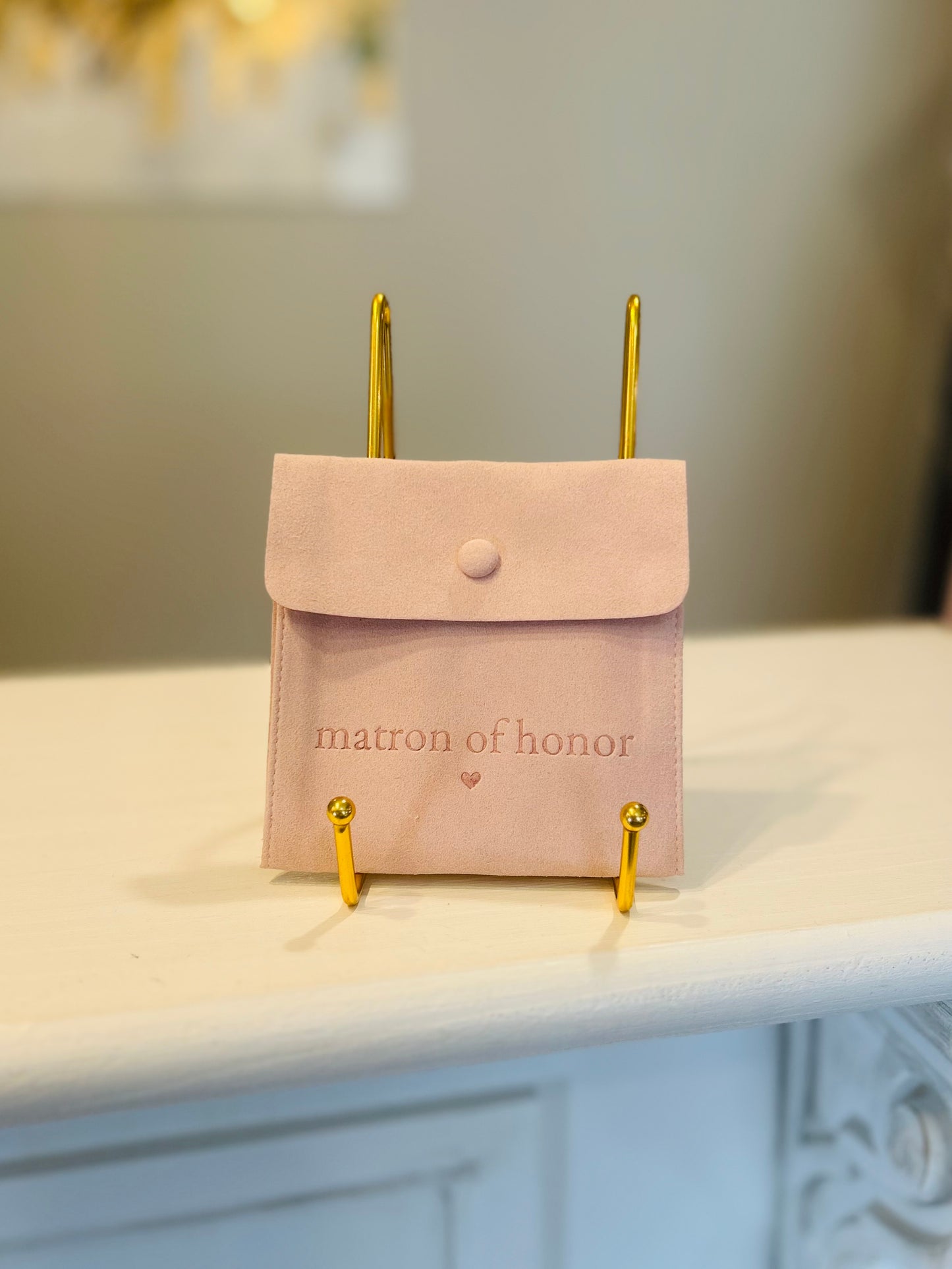 Pink pouch with 'matron of honor' text on a white surface