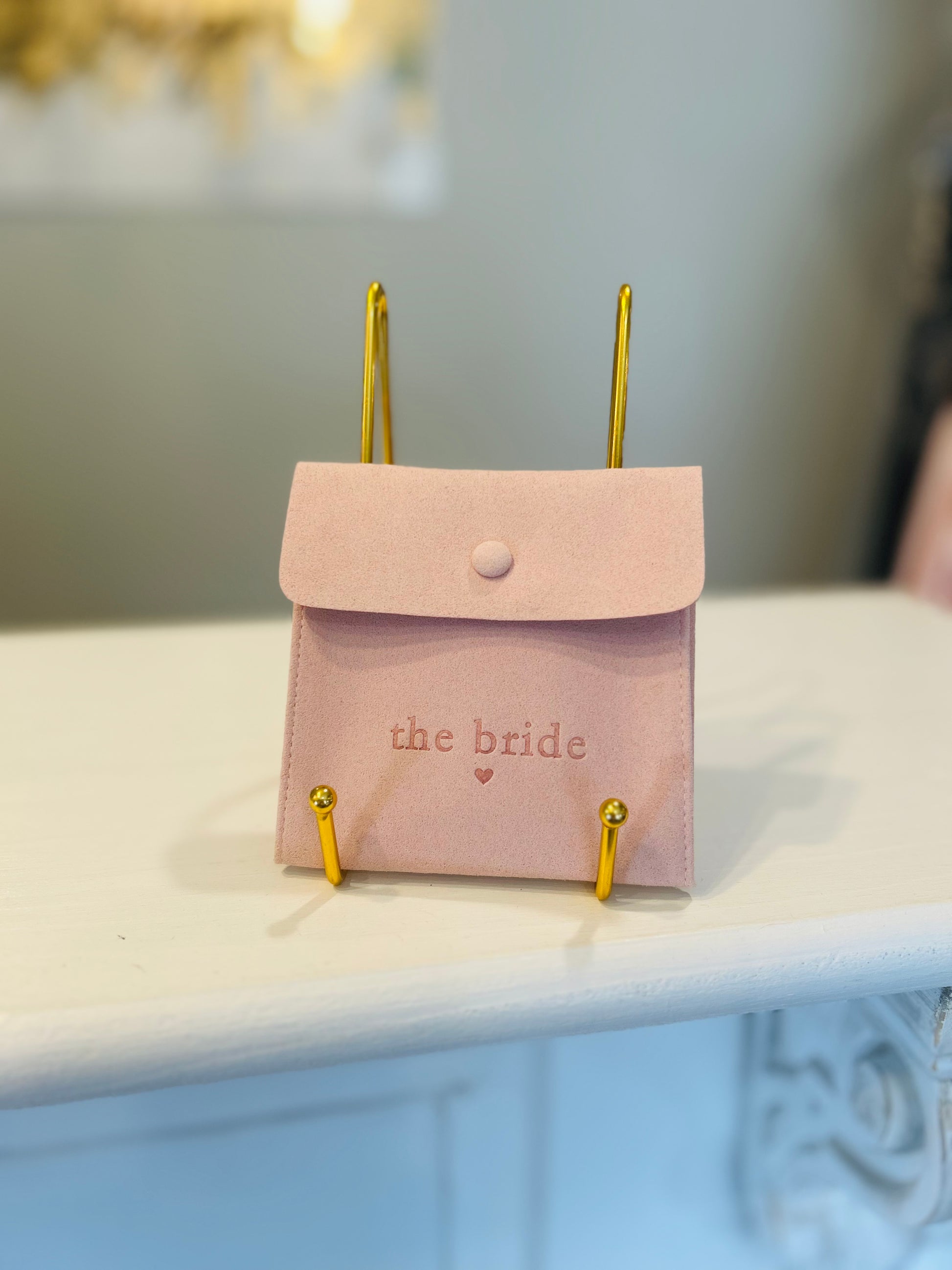 Pink pouch with 'the bride' text on a white surface