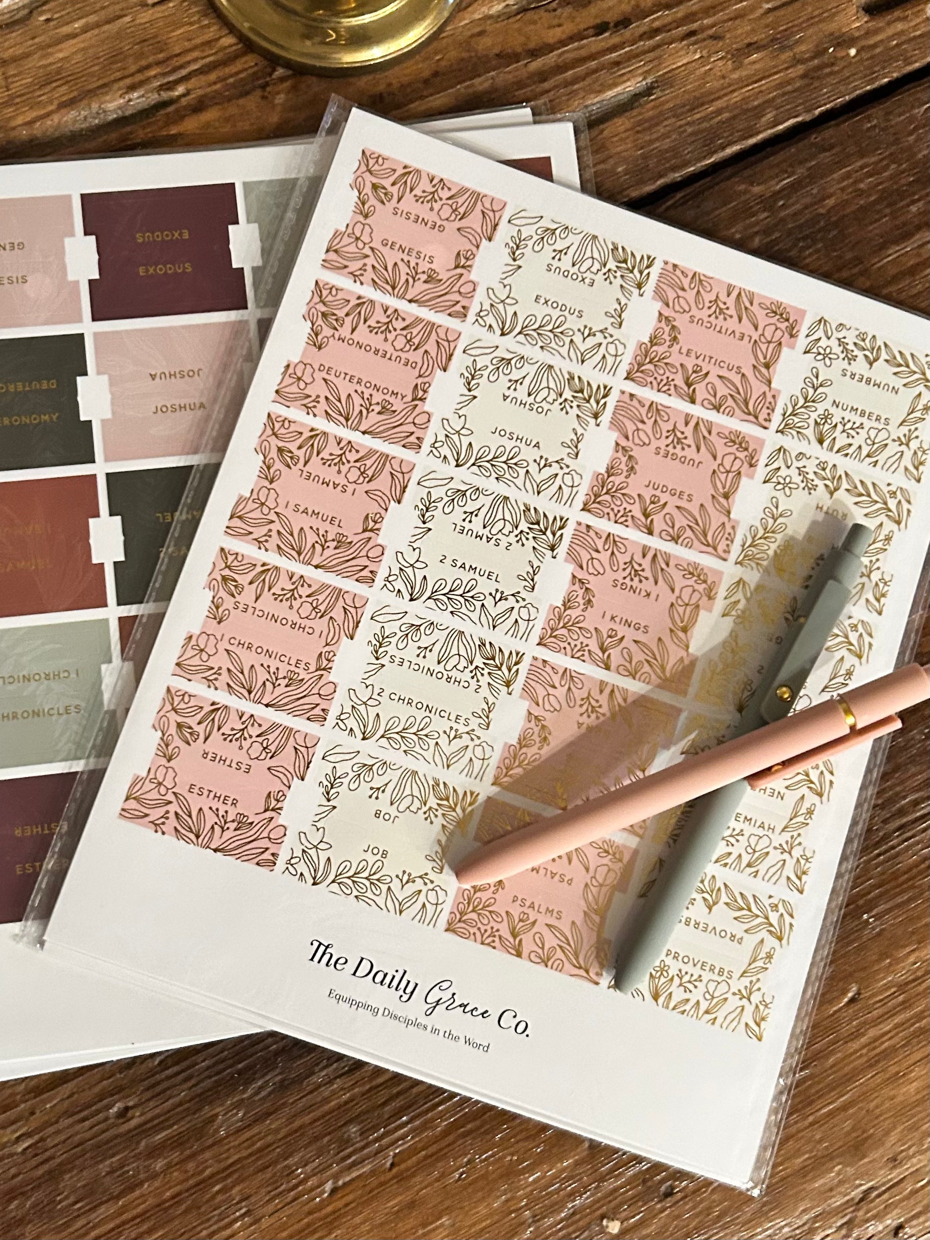 Sheet of decorative bible tabs with a pen on a wooden surface, featuring the Daily Grace Co brand.