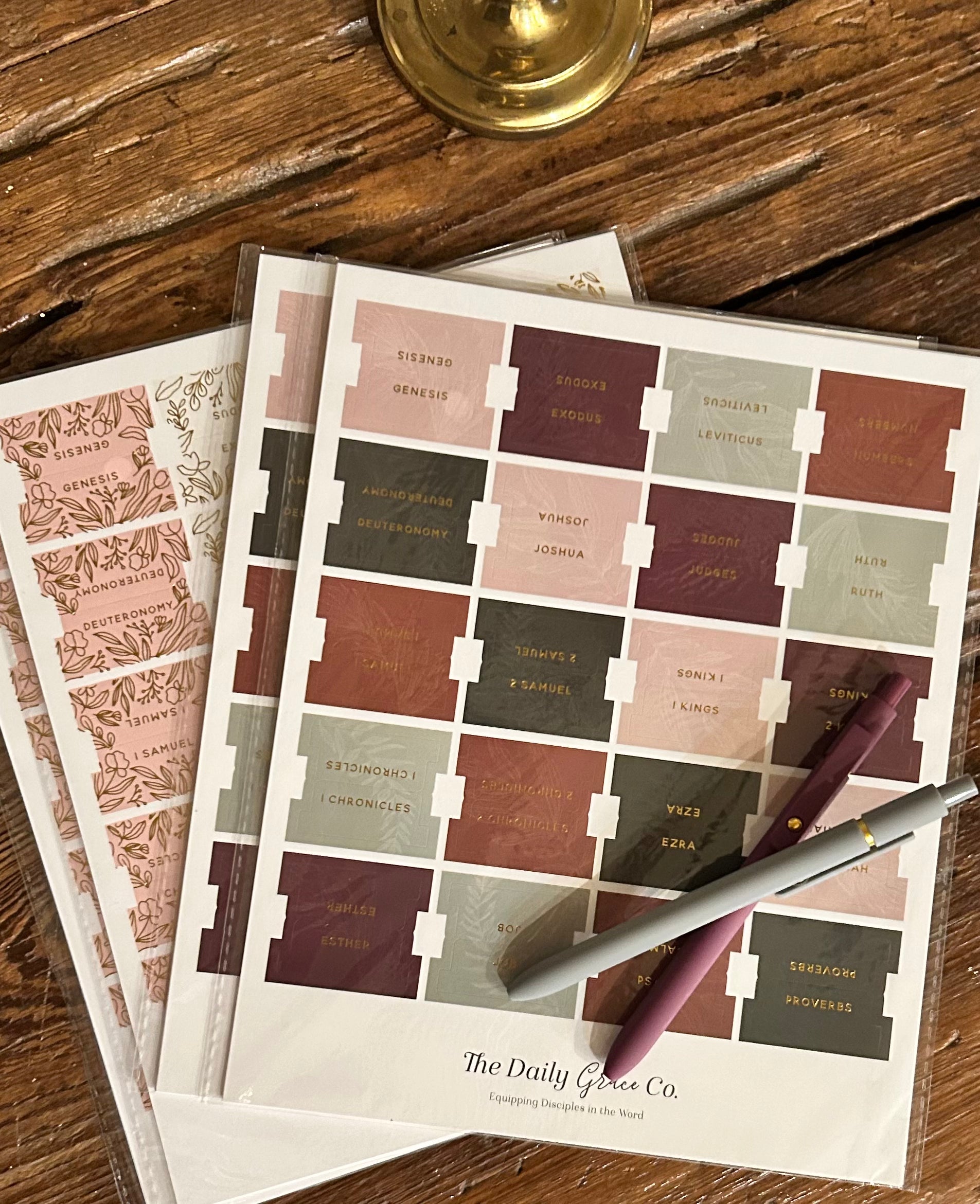 Sheet of decorative tabs with bible text on a wooden surface, featuring 'The Daily Grace Co.' branding.