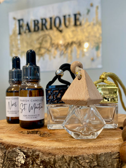 Car diffusers in a rectangle clear glass container with wooden top and diffuser oils in brown glass bottle on a piece of wood