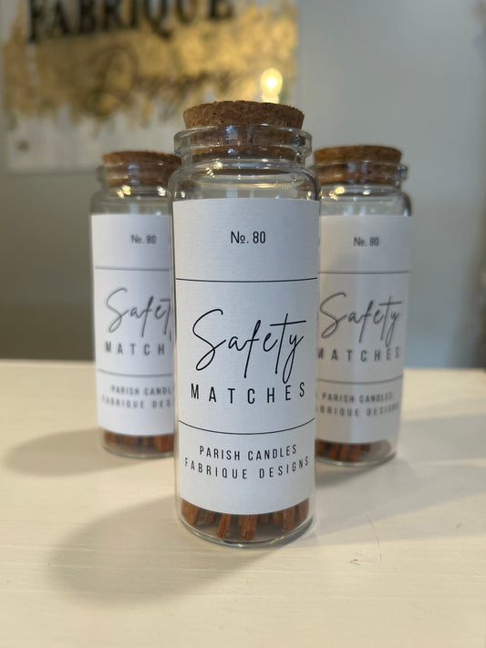 Three jars of safety matches with labels on a reflective surface