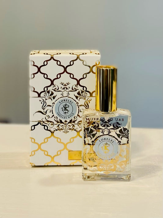 A perfume bottle with a gold cap and clear glass container, accompanied by a box with a decorative gold pattern. The label on the bottle reads 'Shelley Kyle' and 'Perfume & Fragrance'.