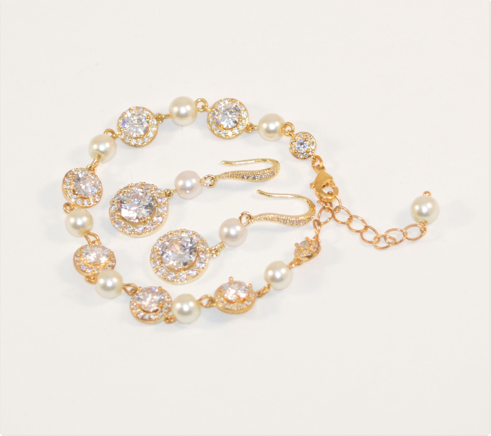 An ivory pearl bridal bracelet and earring set with gold plating and cubic zirconia stones.