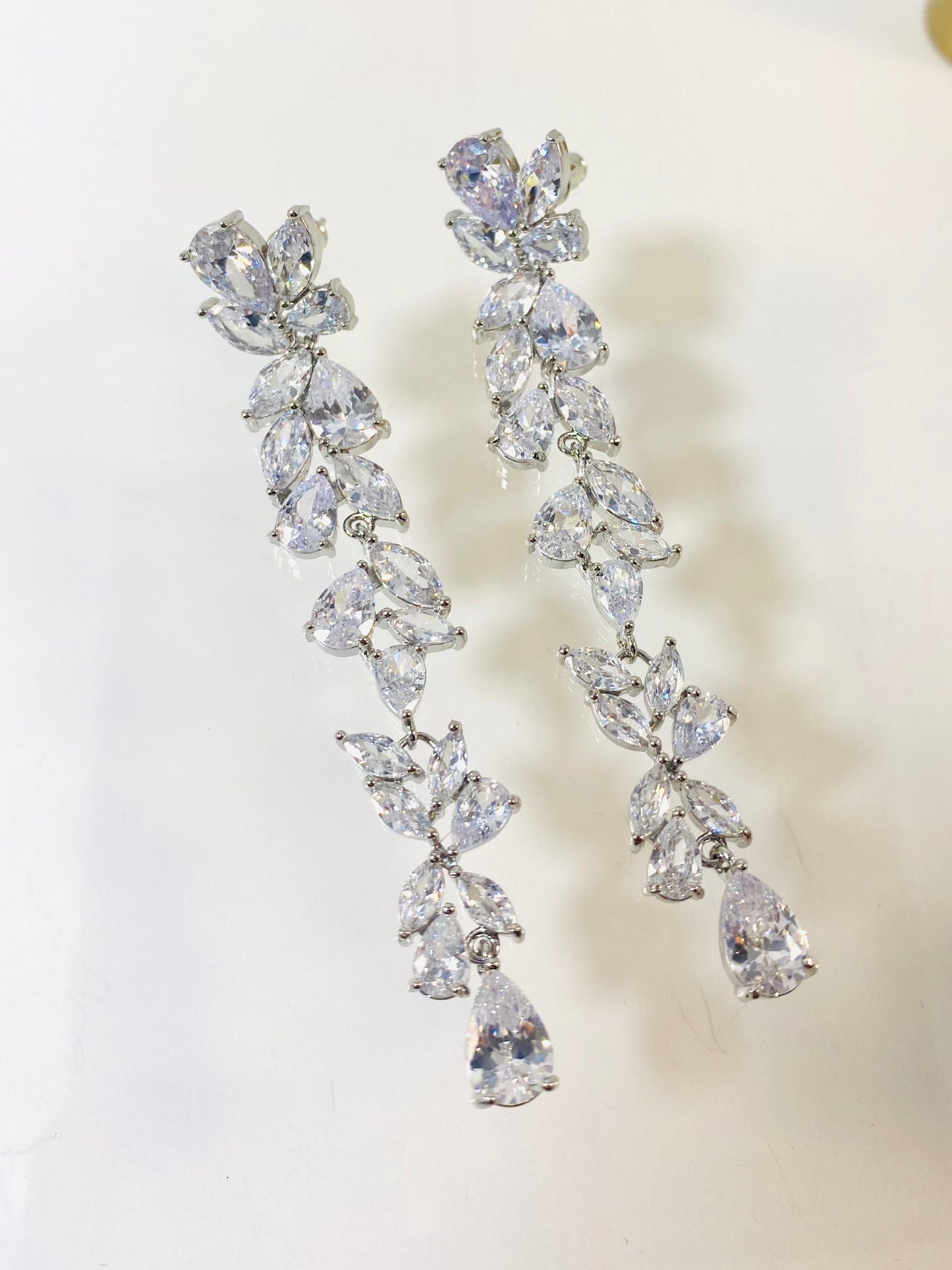 A pair of silver-colored bridal earrings featuring a floral design with marquis, teardrop, and round cubic zirconia stones.