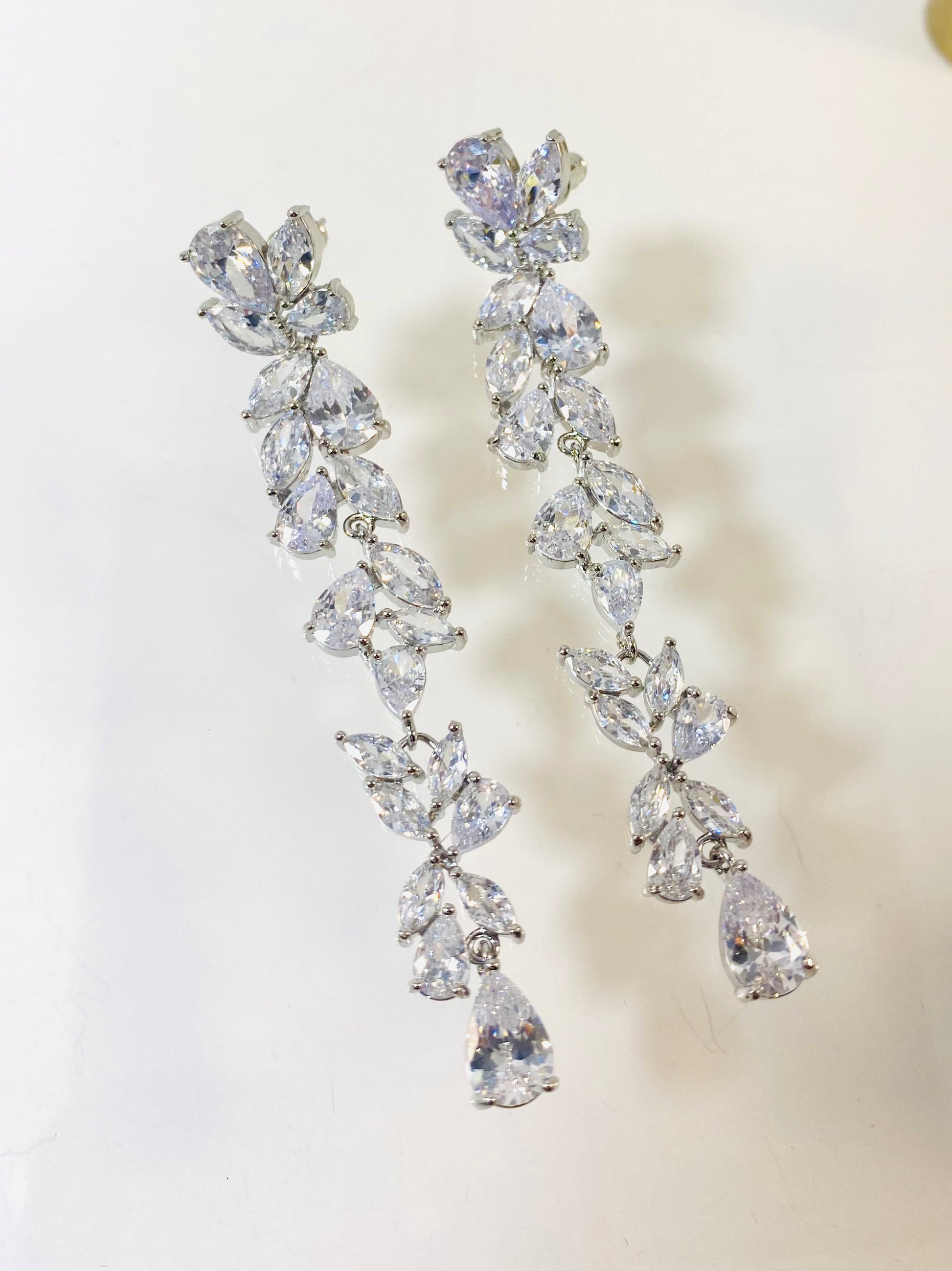 A pair of silver-colored bridal earrings featuring a floral design with marquis, teardrop, and round cubic zirconia stones.
