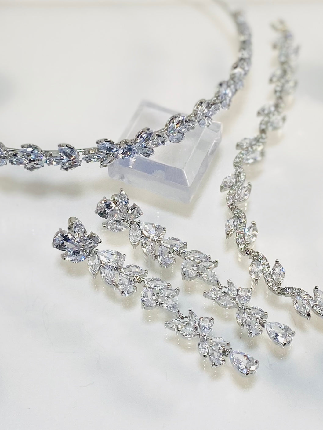 Cubic zirconia dangle earrings with marquis and teardrop stones, headband in matching stones on a white background.