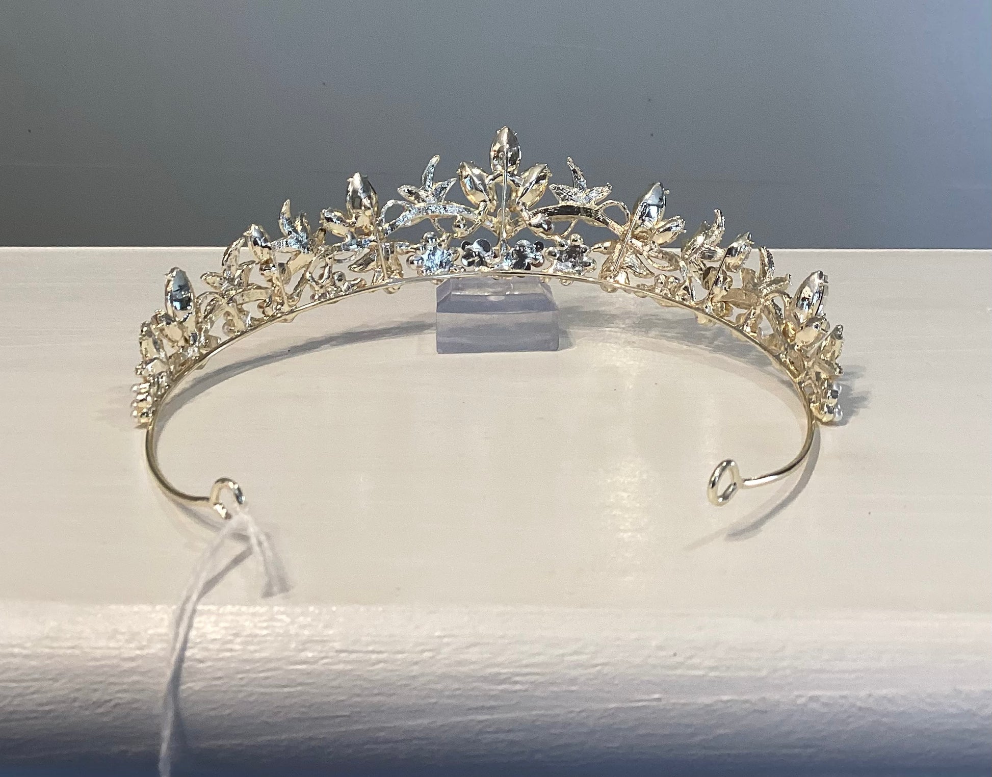 Gold tiara with pearls and rhinestones on a white counter.
